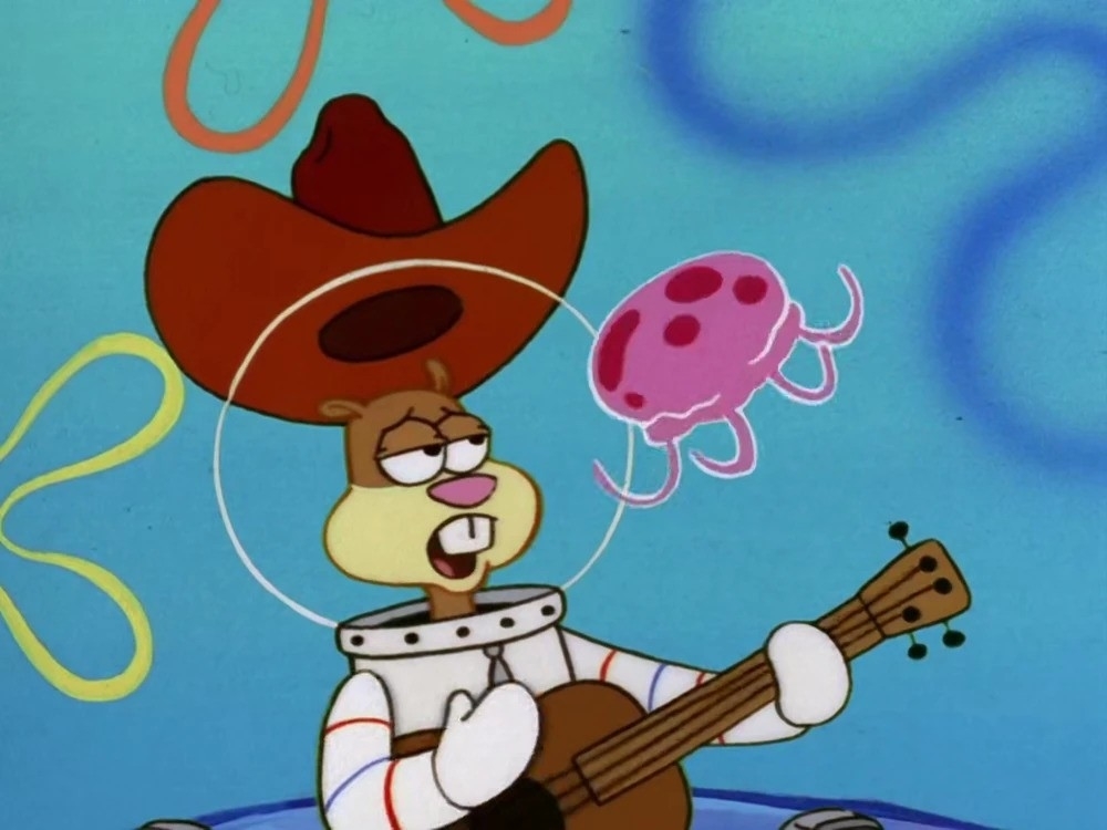 Sandy Cheeks in a cowboy hat plays guitar with a jellyfish floating nearby