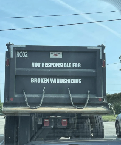 Back of a truck with a sign reading &quot;NOT RESPONSIBLE FOR BROKEN WINDSHIELDS.&quot;