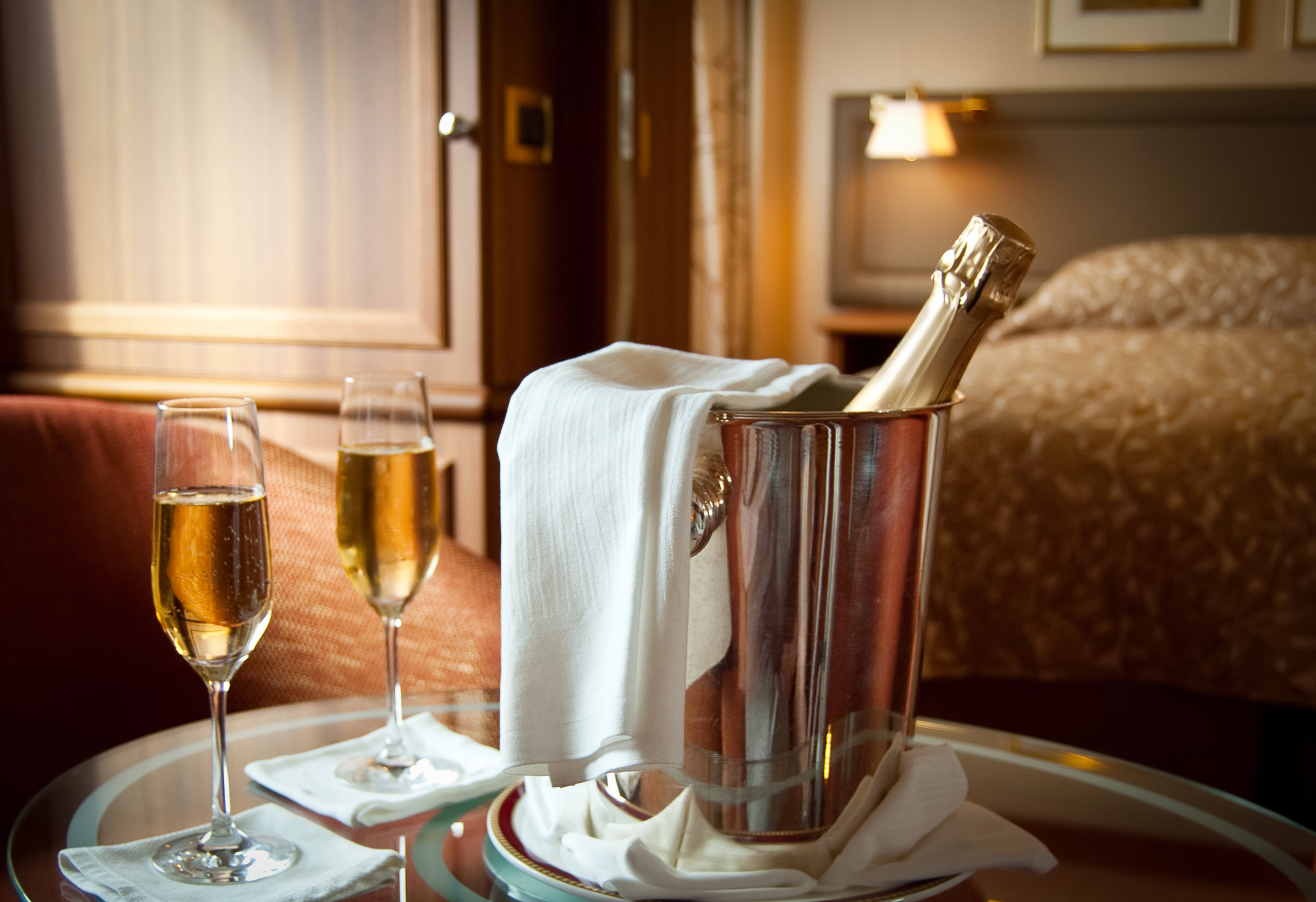 Two flutes of champagne with a bottle in an ice bucket, set on a luxury room service tray