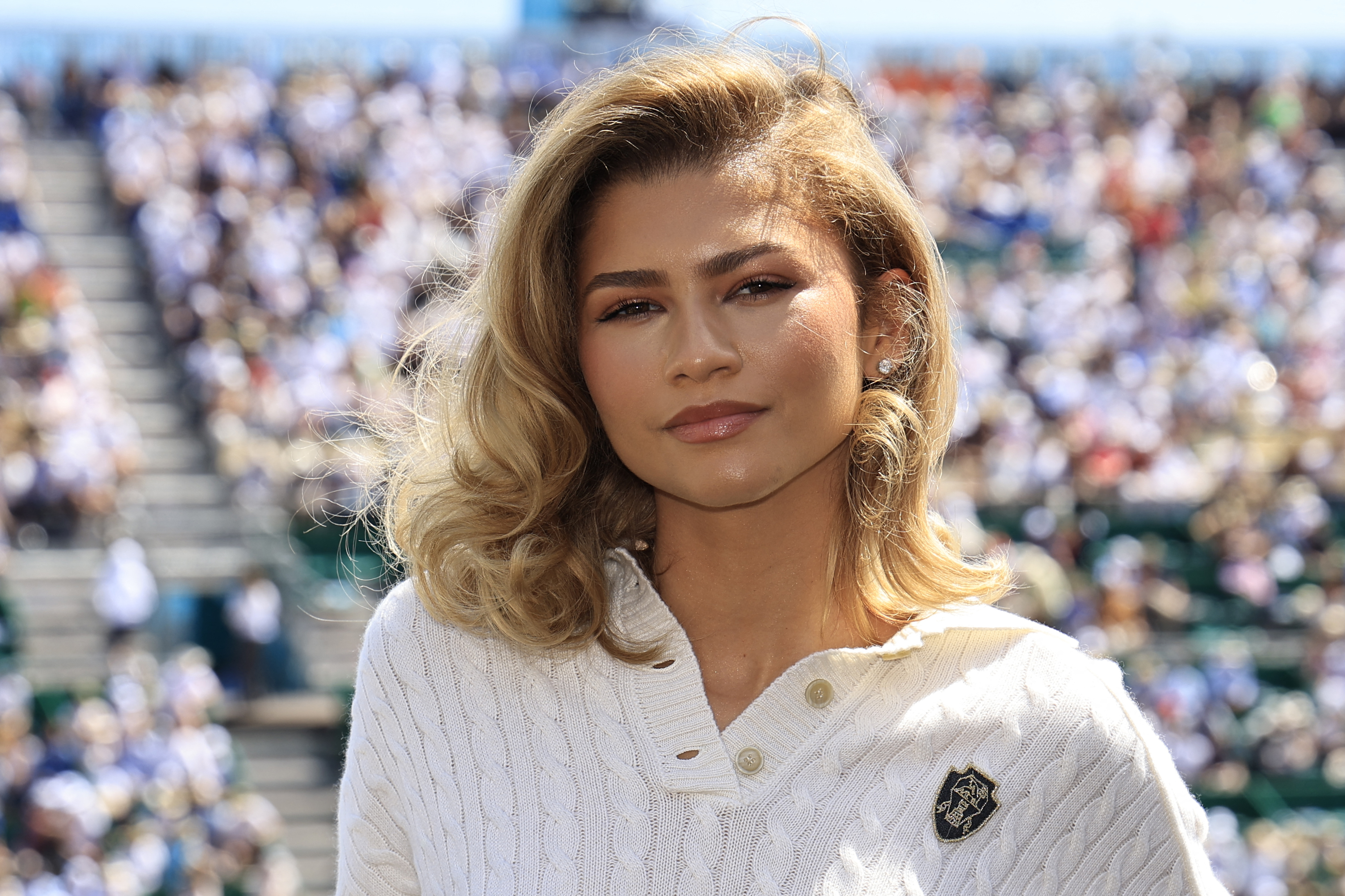 Zendaya wearing a white polo shirt with a knit design at an outdoor event