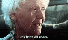Elderly woman in a film with subtitle &quot;It&#x27;s been 84 years,&quot; expressing reminiscence