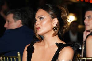 Woman wearing black dress with bow details on shoulders, hoop earrings, at an event