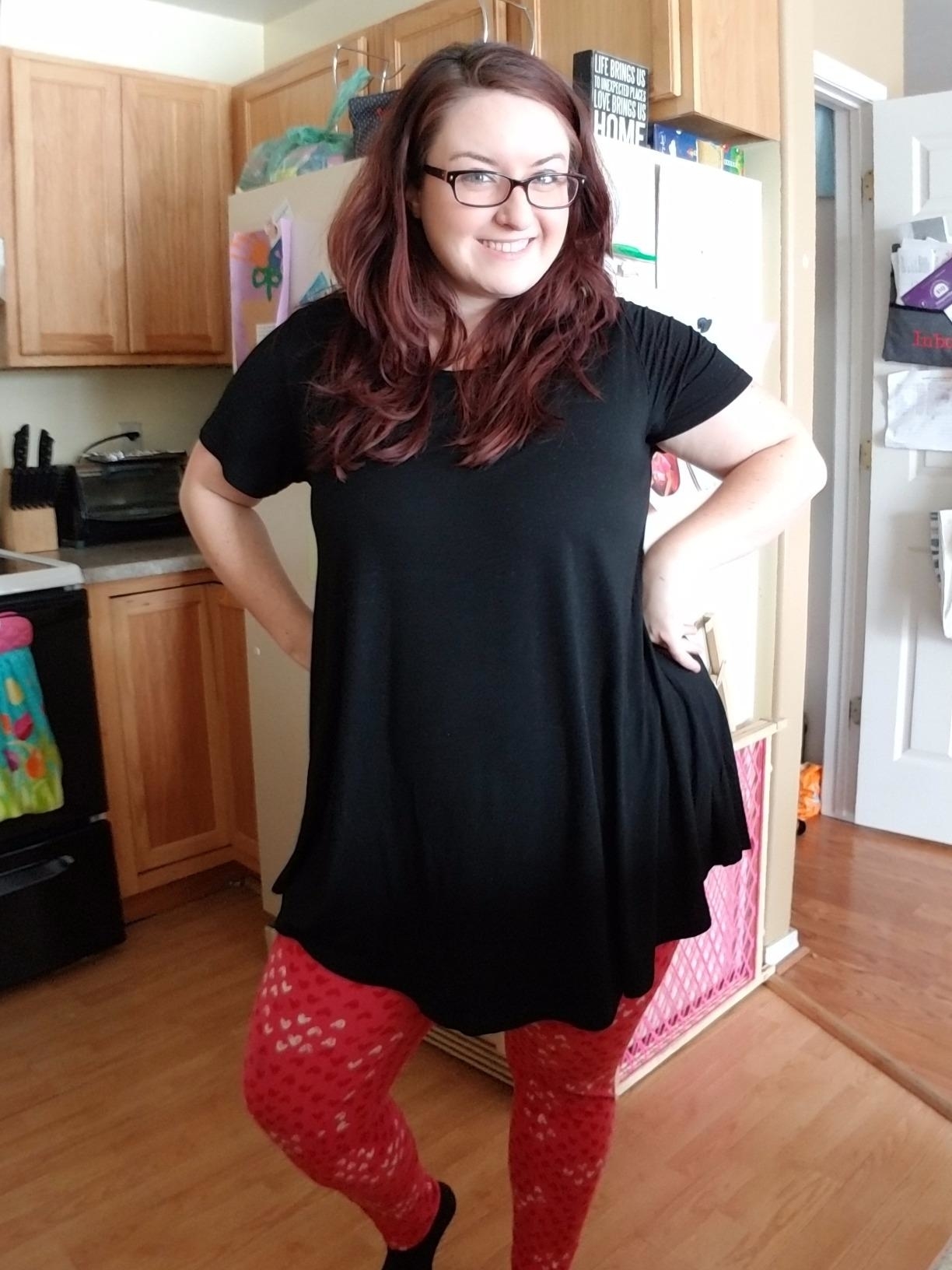 Reviewer's photo of them wearing the tunic in black, styled with red leggings