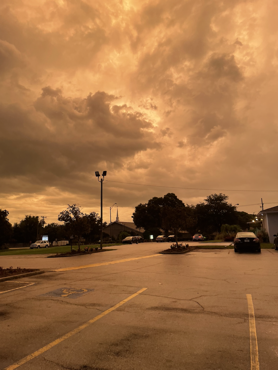 Sky with dramatic clouds over a parking lot, giving a vivid, almost fiery appearance to the scene