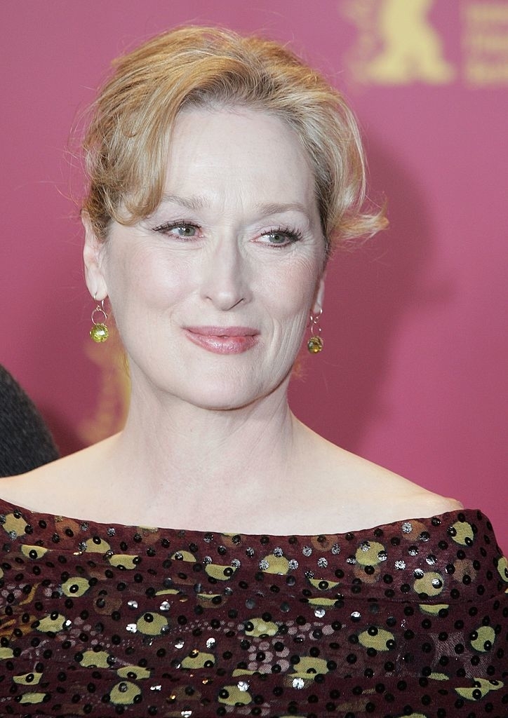 Meryl Streep smiling in a sequined gown with a sheer neckline, wearing dangling earrings