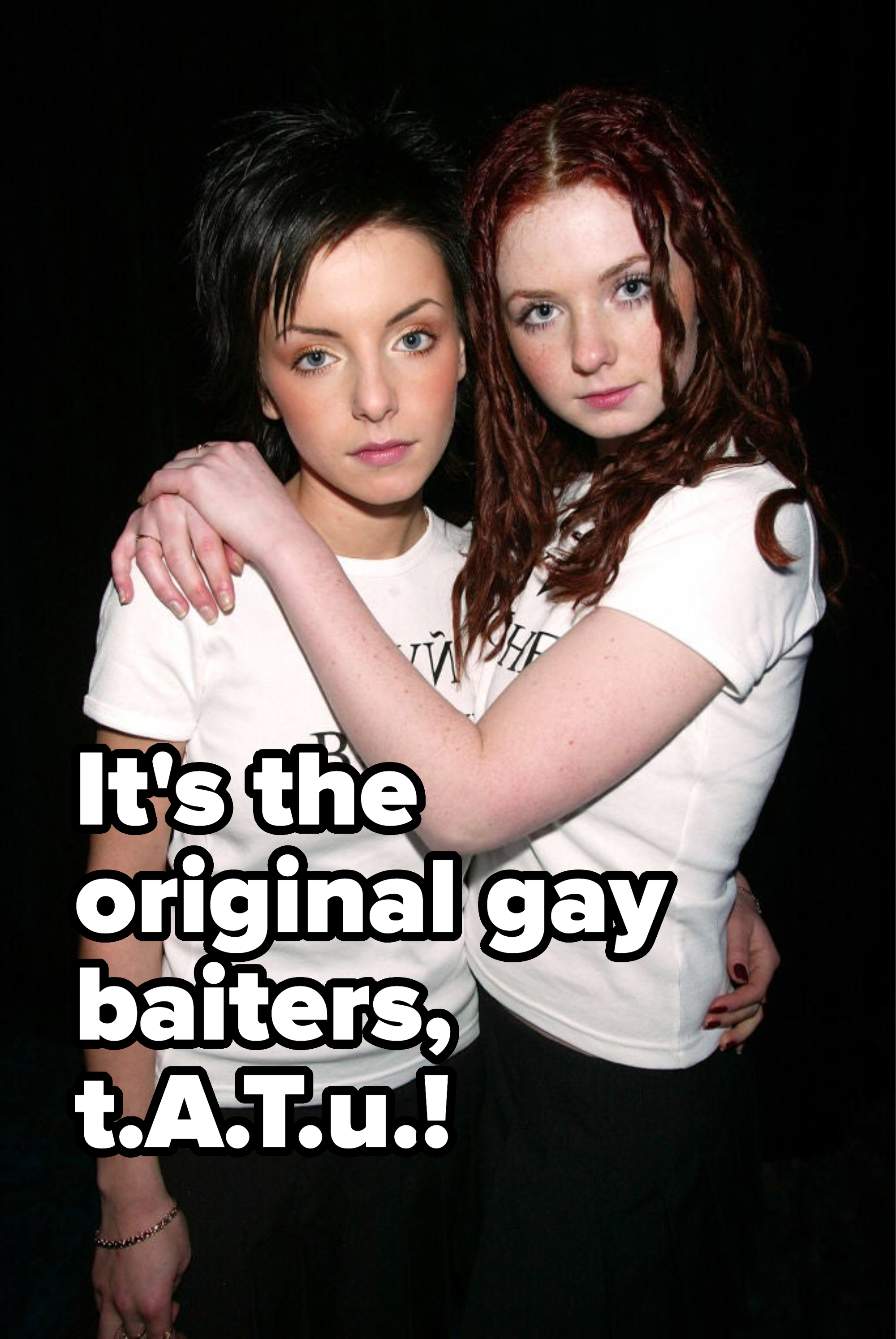 Two women in white tees stand close together, one resting her arm on the other's shoulder