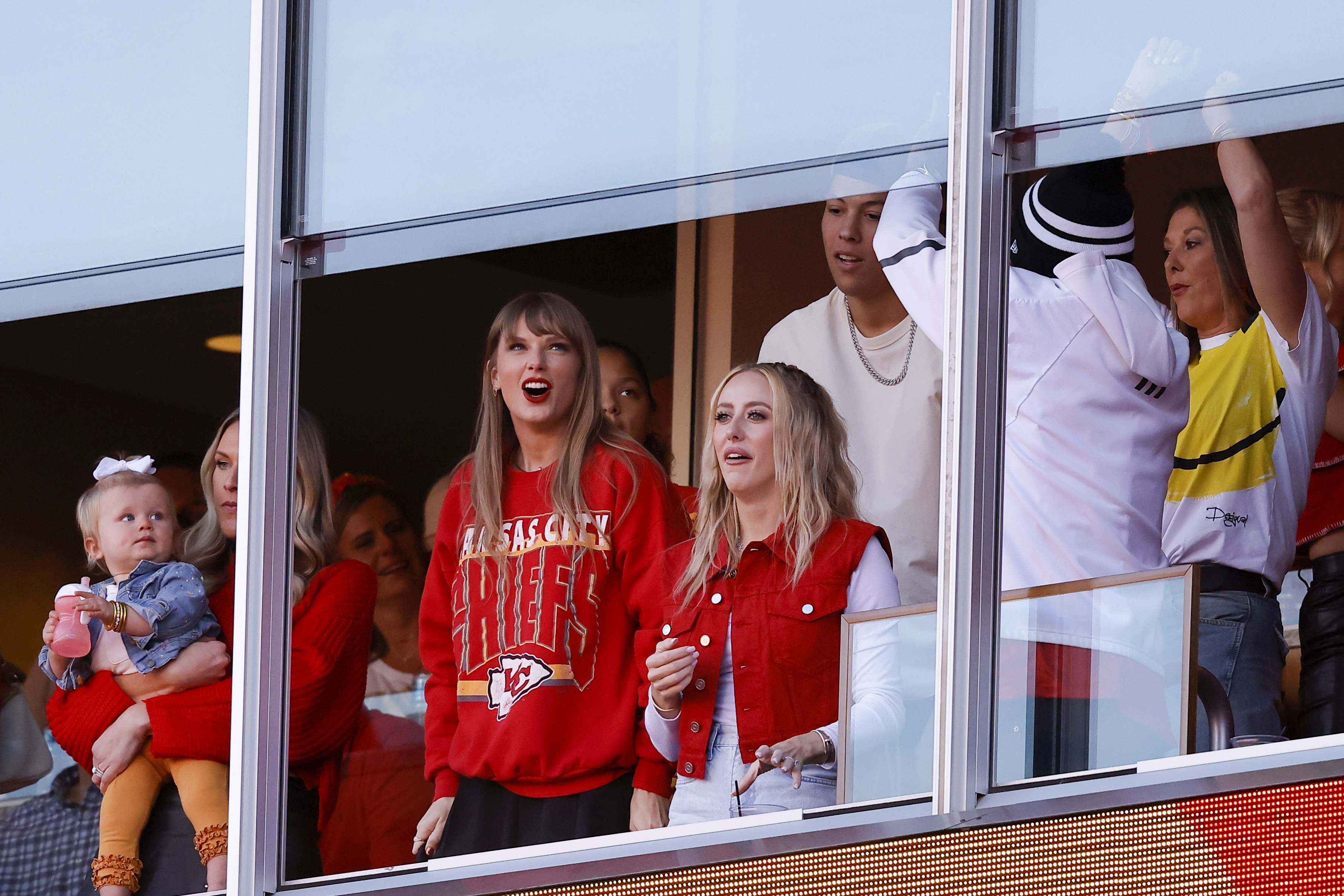 Group of people including Taylor Swift in a VIP box cheering on Kelce and his team