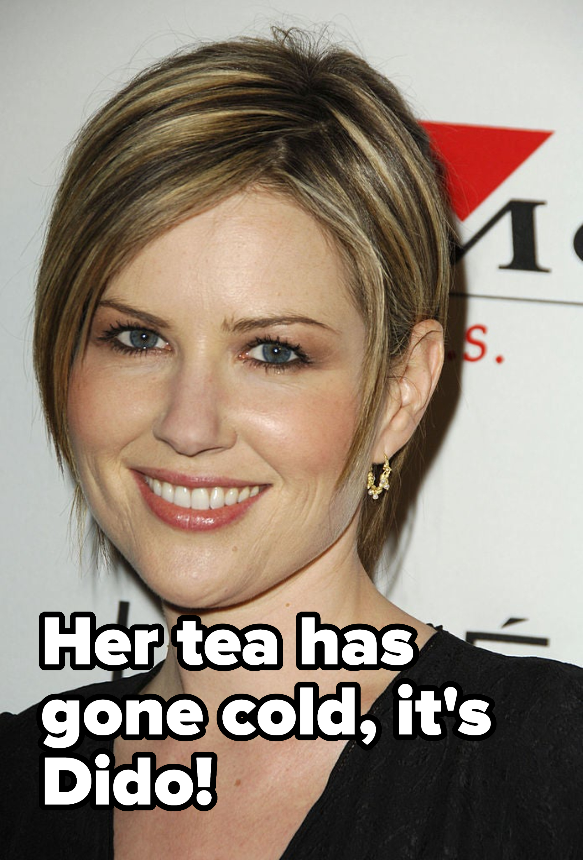 Woman with short hair wearing earrings smiling at a media event