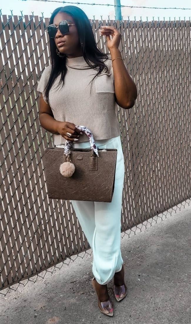 Reviewer's photograph of them wearing the lounge acceptable successful the colour khaki white, styled with wide pointy-toed pumps, a brownish handbag, and sunglasses