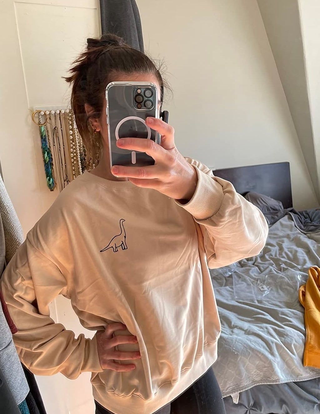 Reviewer&#x27;s photo of them wearing the sweatshirt in the color apricot styled with black leggings, taking a mirror selfie with a phone