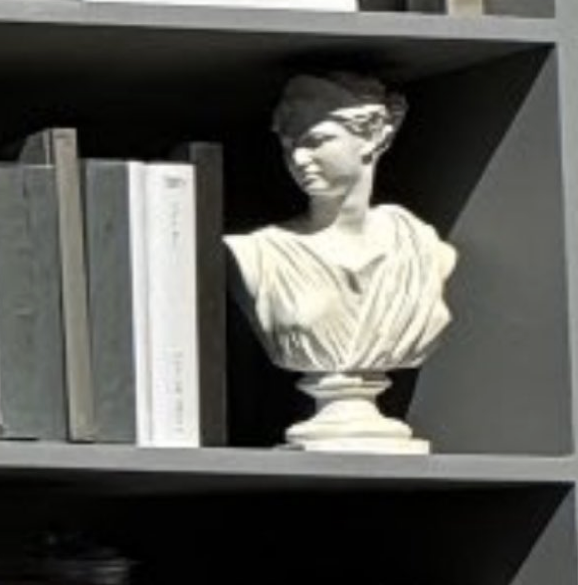 Bust of a classical figure next to books on a shelf