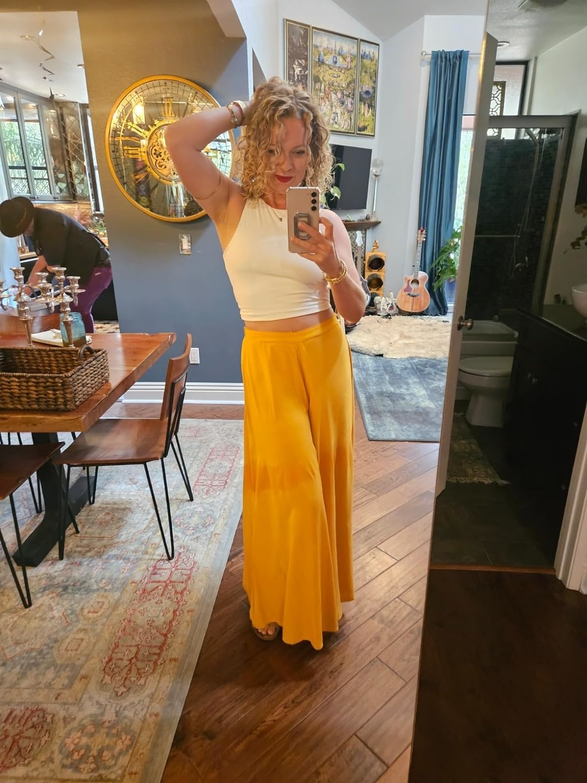 Reviewer's photo of them wearing a white cropped tank, styled with wide leg yellow pants