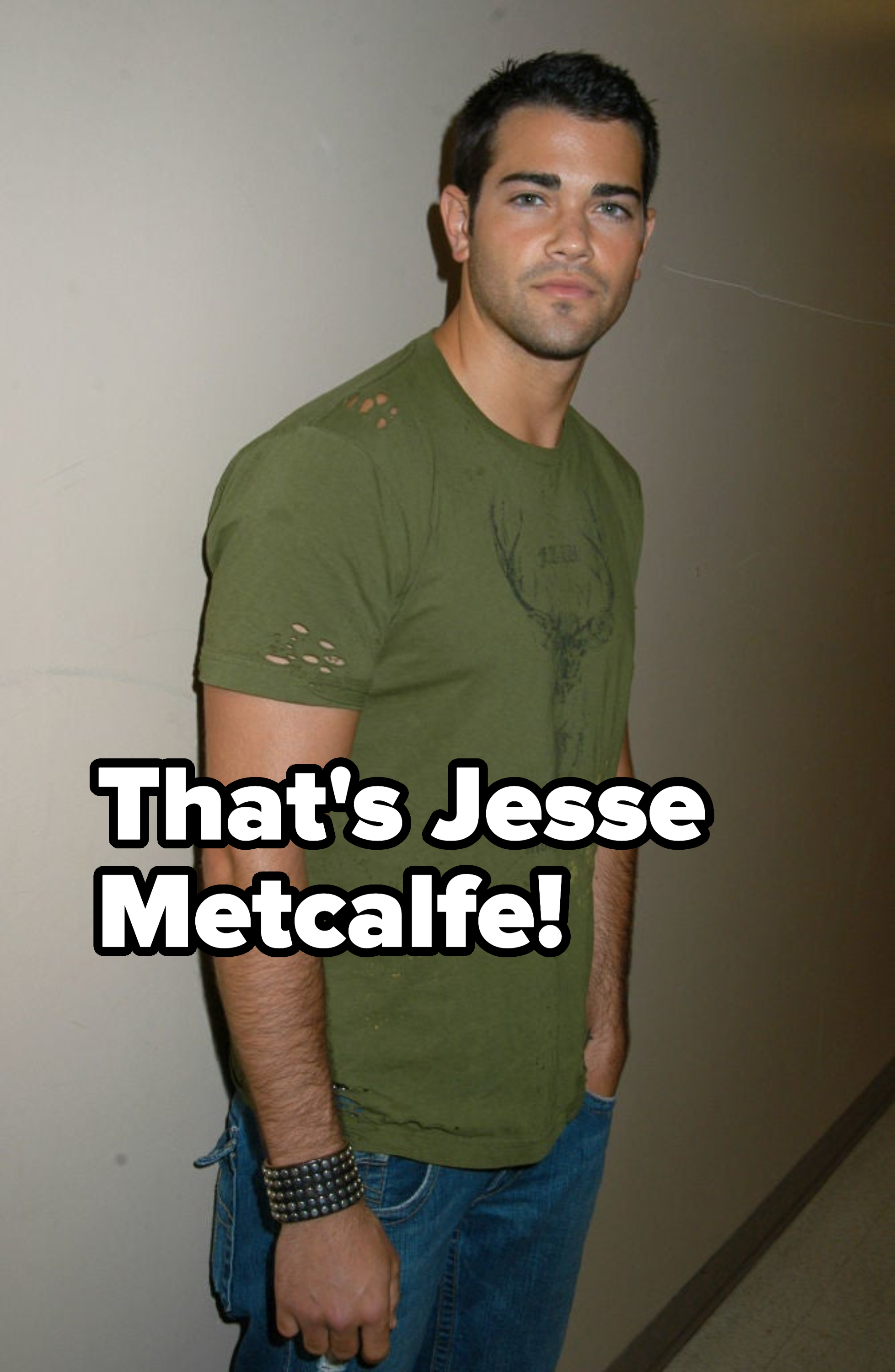 Jesse Metcalfe standing casually in a green t-shirt with distressed details, wearing a bracelet