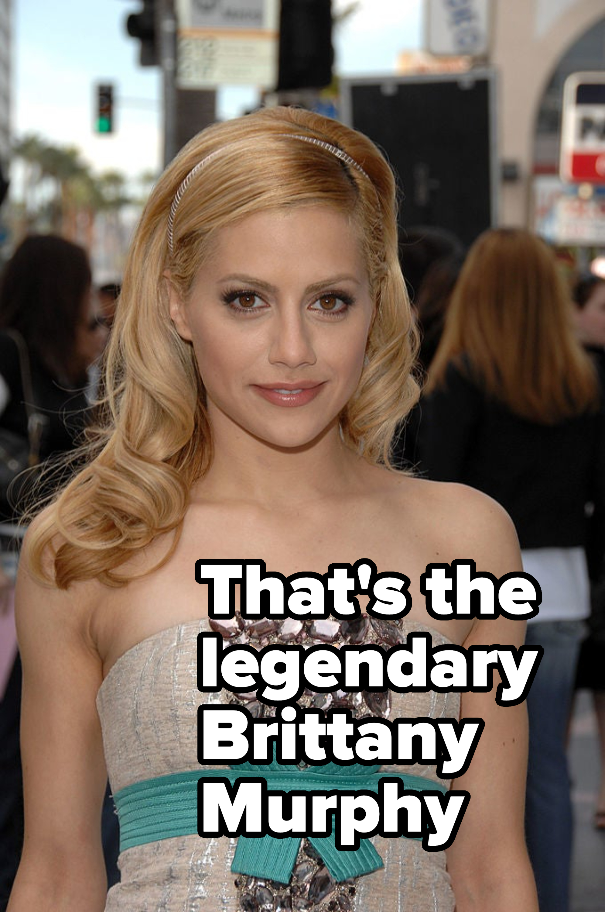 Person in embellished strapless dress with a teal waist bow, with a headband and wavy hair, at a public event