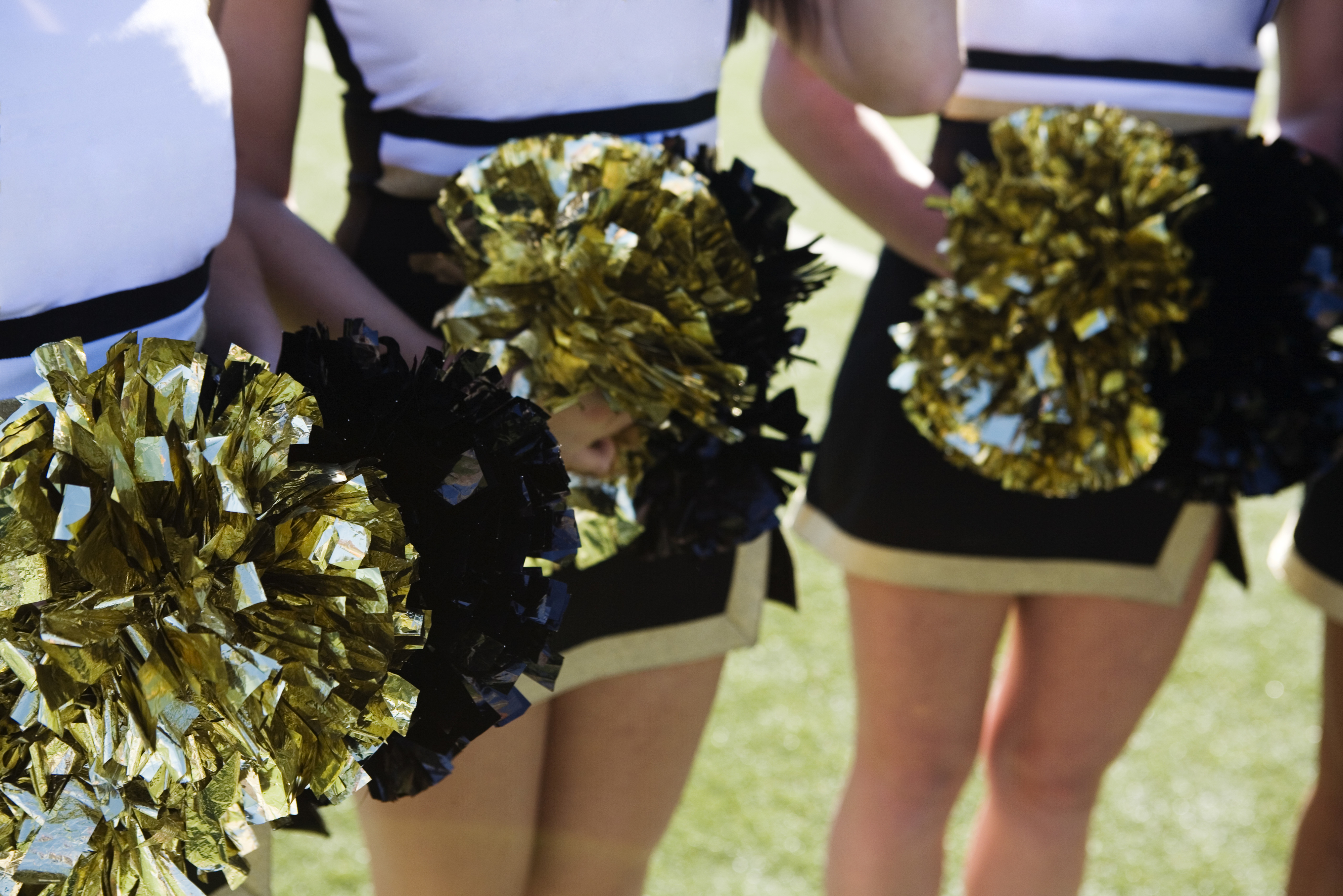 Cheerleaders holding gold and black pom-poms, focusing on team spirit at a work event