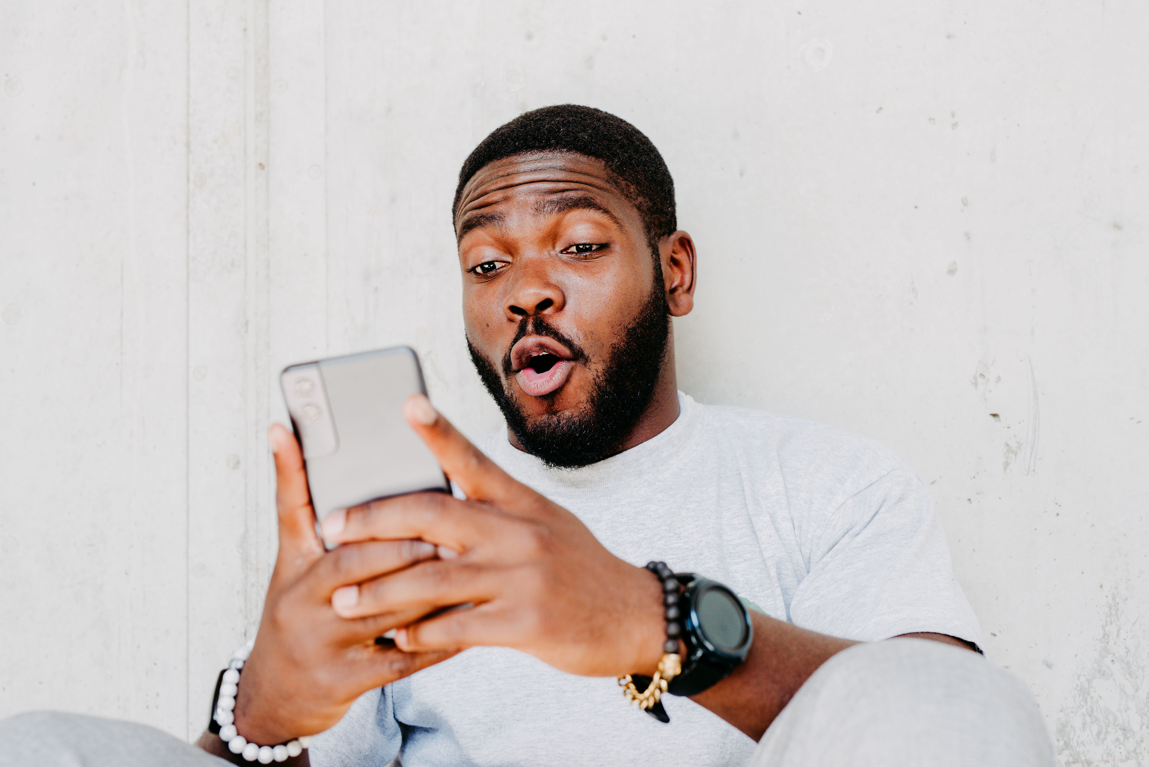 Man with surprised expression looking at smartphone, reflecting work-related news
