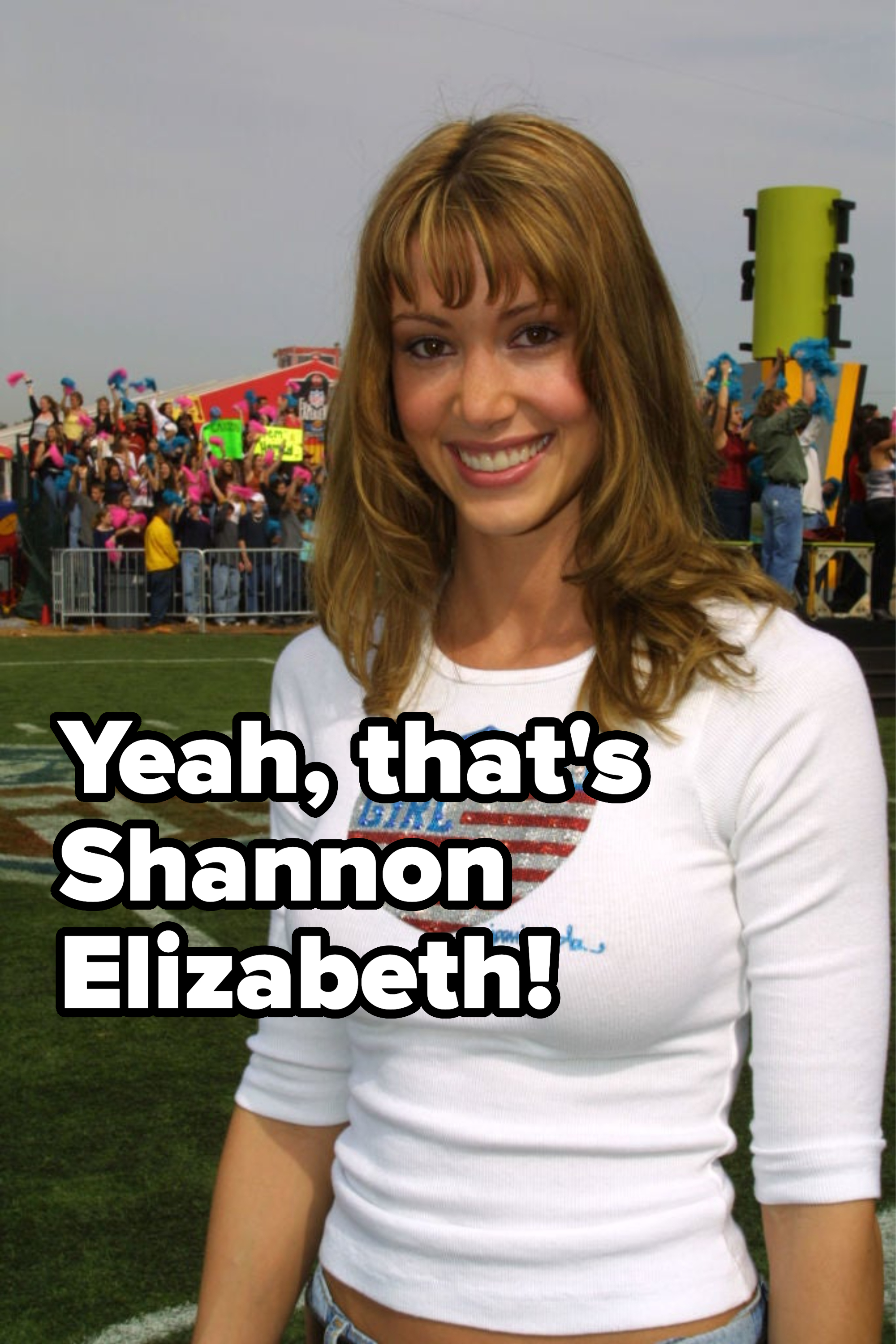 Woman smiling for the camera wearing a white top with &quot;American Girl&quot; graphics, at an outdoor event