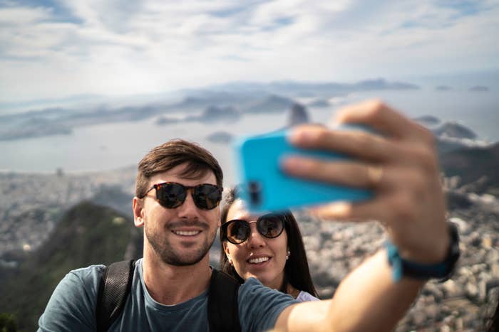 Couple taking a selfie with a scenic overlook of a city and water in the background