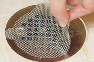 Hand lifting a mesh drain cover from a floor drain