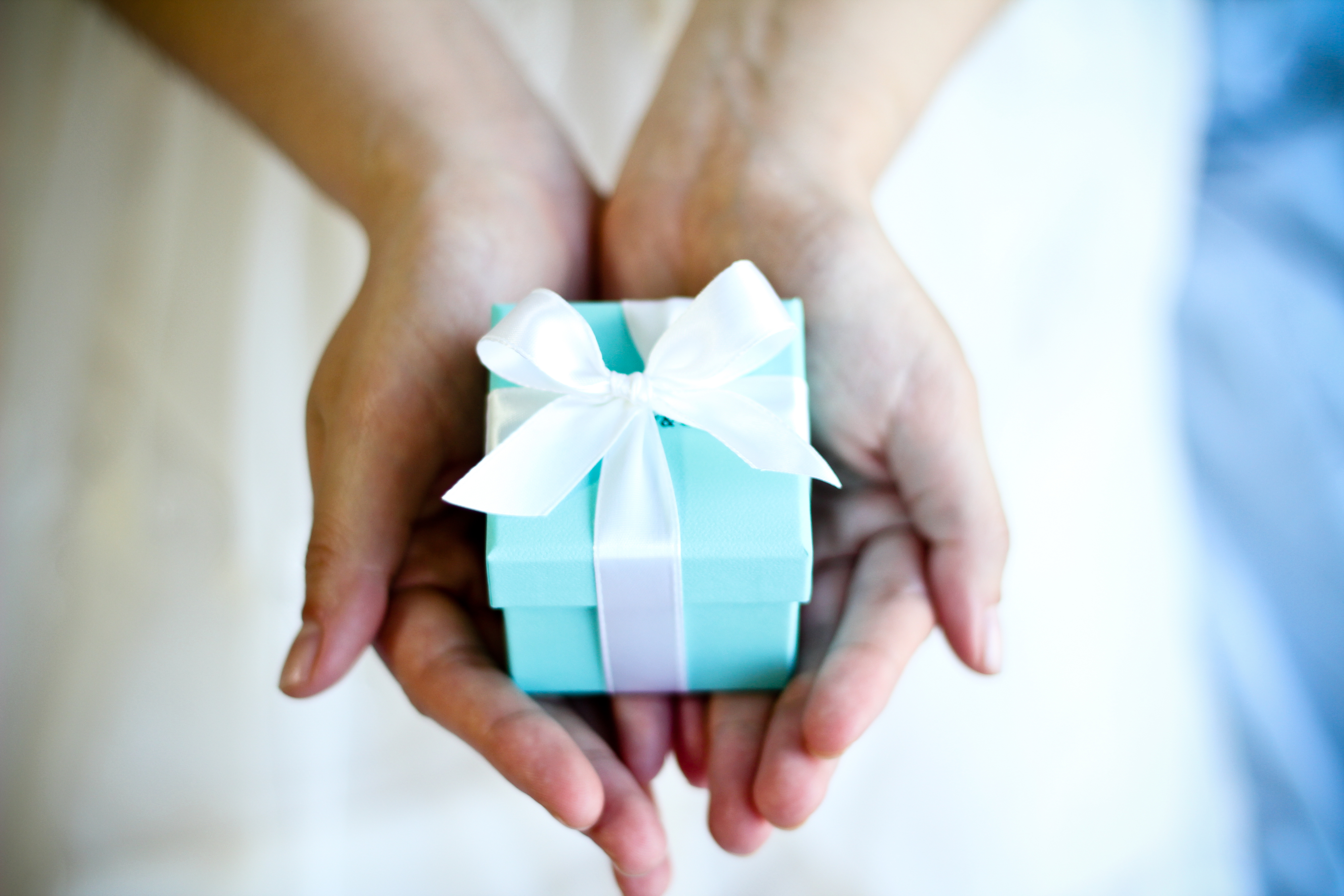 Person holds a small gift box with a bow, symbolizing a token of affection or a romantic gift