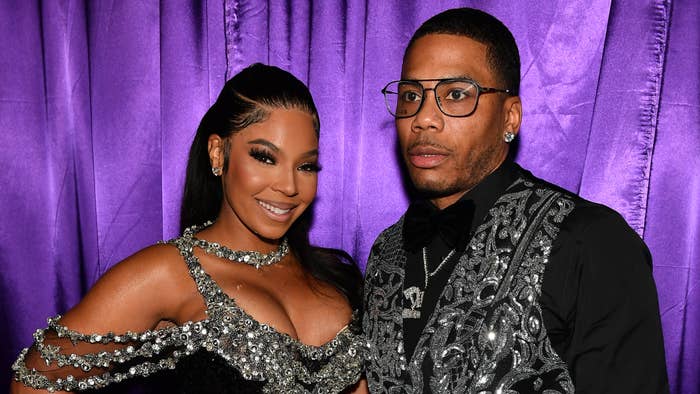 Ashanti and Nelly pose together; one in a sparkling dress with cut-outs, the other in a patterned black suit