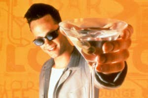 Vince Vaughn holding out a martini in sunglasses and a jacket.