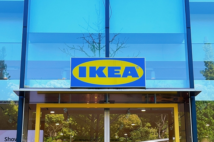 IKEAの店舗入り口と青空、透明なガラスに木の映り込み。