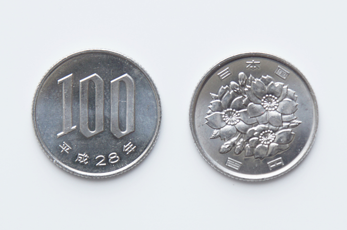 表と裏の日本の100円硬貨が並んでいる。