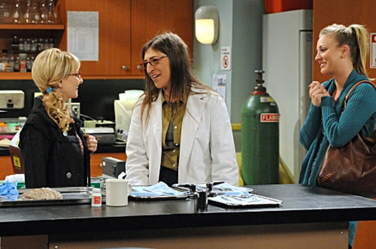 Three characters from &quot;The Big Bang Theory&quot; in a lab, one in a white coat, others in casual attire