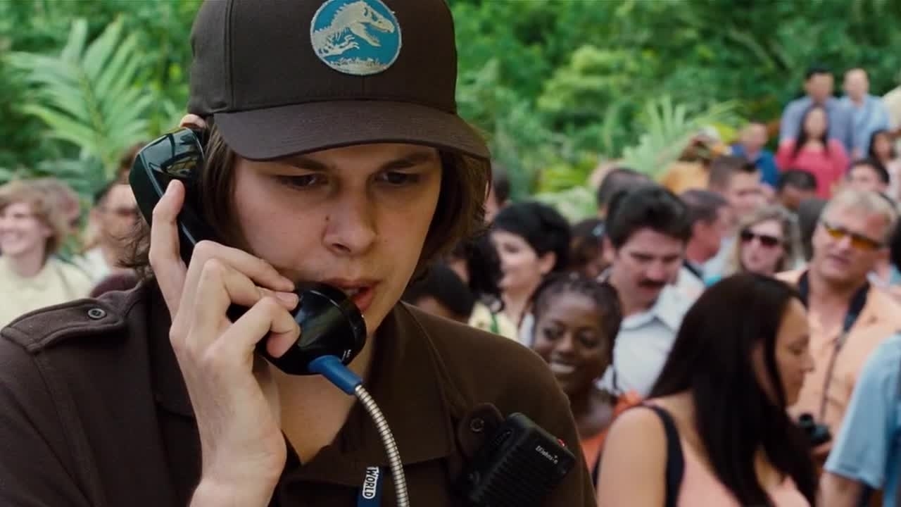 A person wearing a cap, speaking into a corded phone, with a crowd in the background