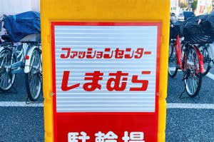 Sign in Japanese script on a yellow stand with bicycles in the background