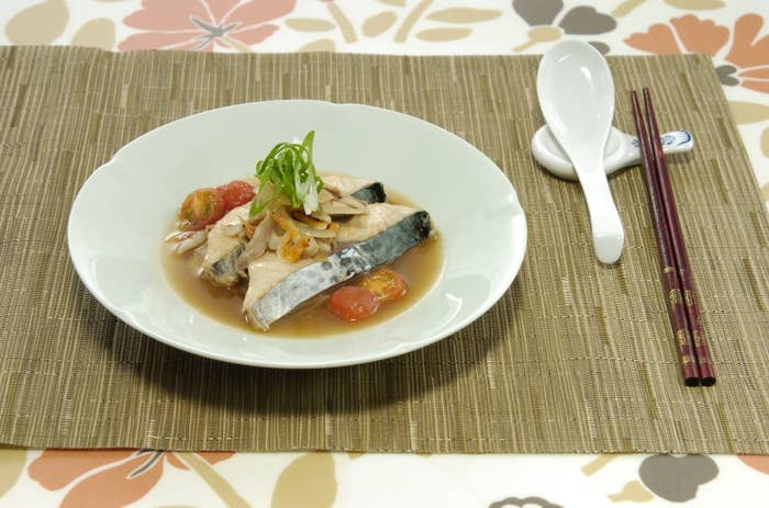 皿に盛られた魚料理、添えられたスプーンと箸があります。
