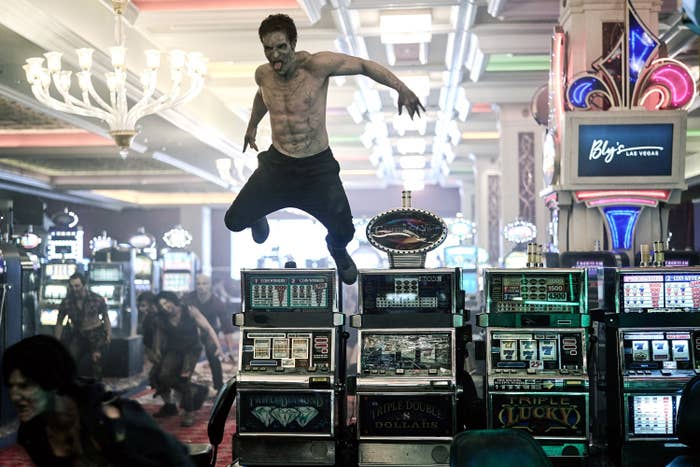 Shirtless zombie standing on slot machines in a chaotic casino scene from the film &quot;Army of the Dead.&quot;