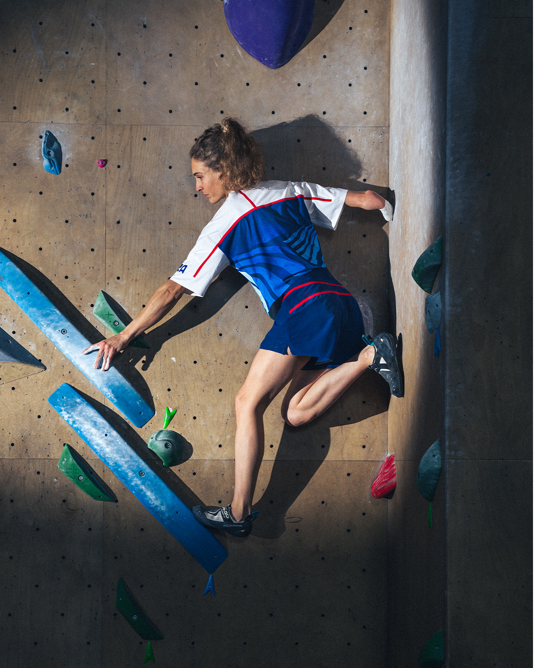 Woman indoor rock climbing, in athletic wear, focused on navigating the wall