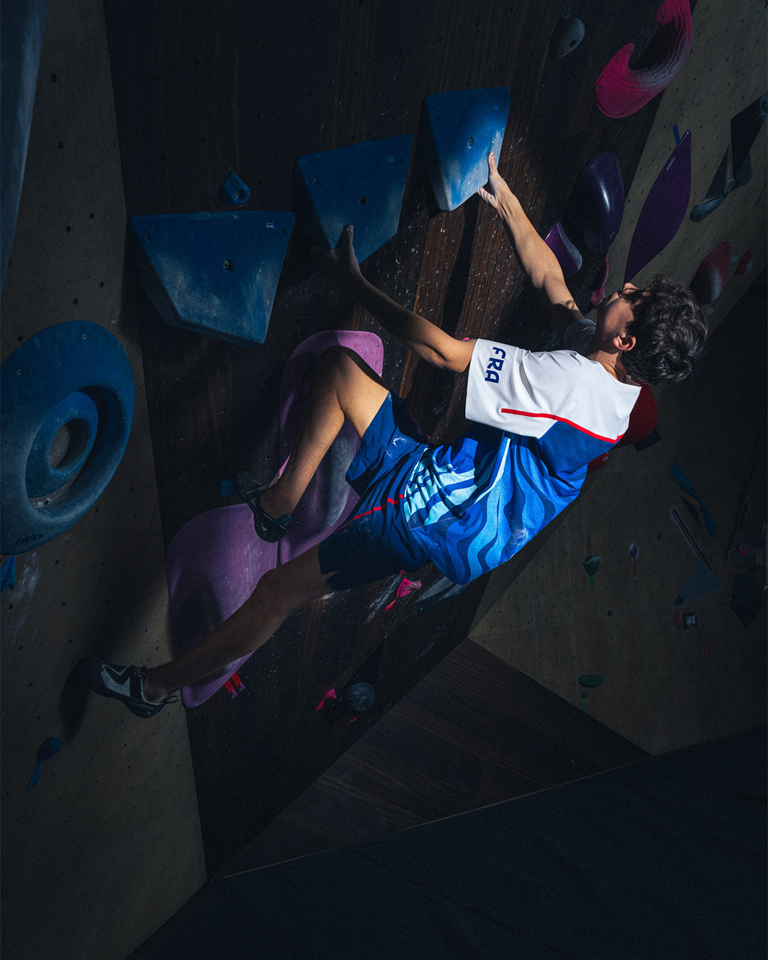 Climber in sportswear ascending a bouldering wall, focusing on grip and technique