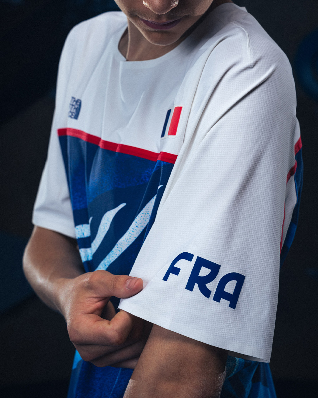 Person adjusting a sports jersey with &quot;FRA&quot; on the sleeve, indicating a French team uniform