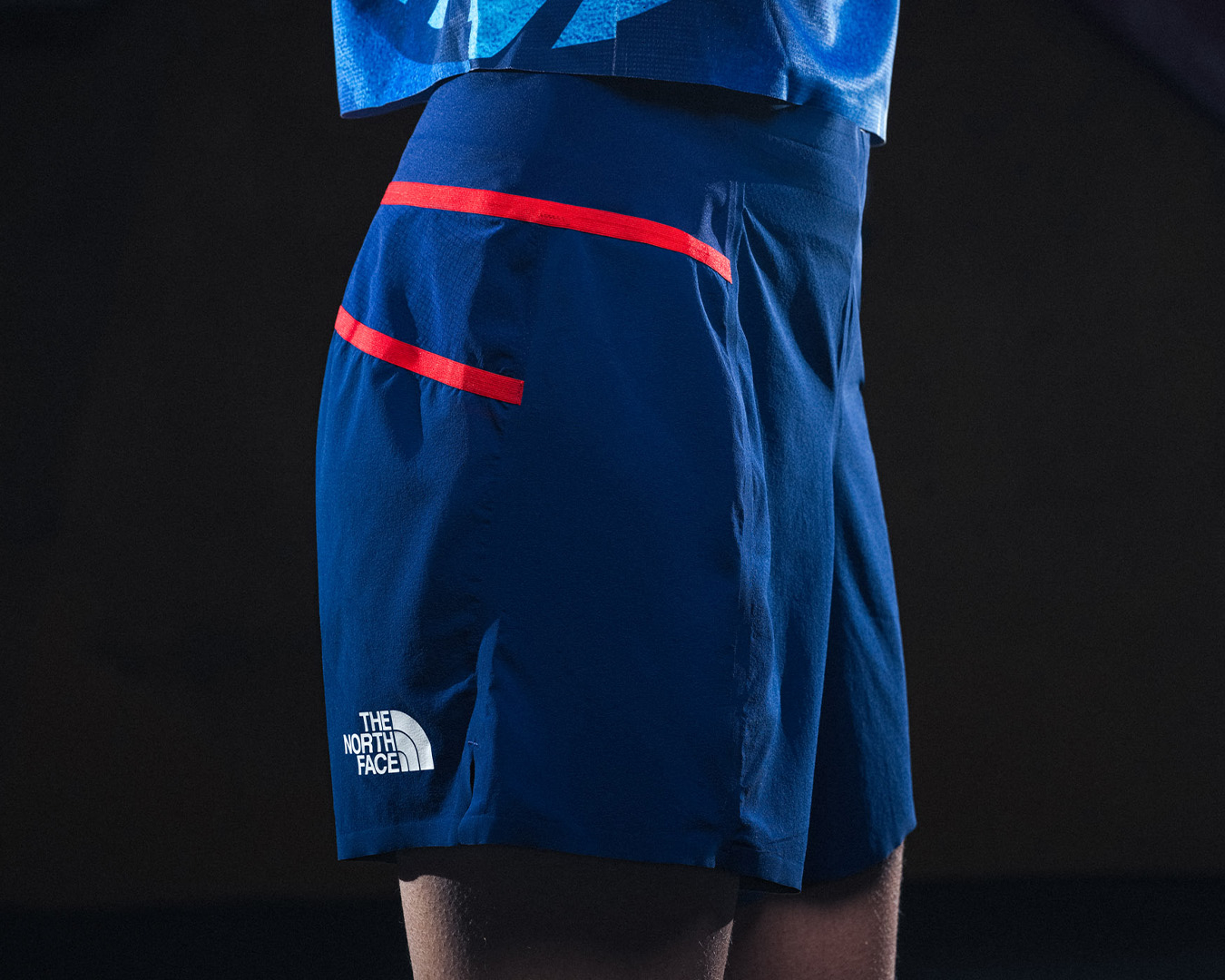 Close-up of North Face blue shorts with a red stripe and logo detail