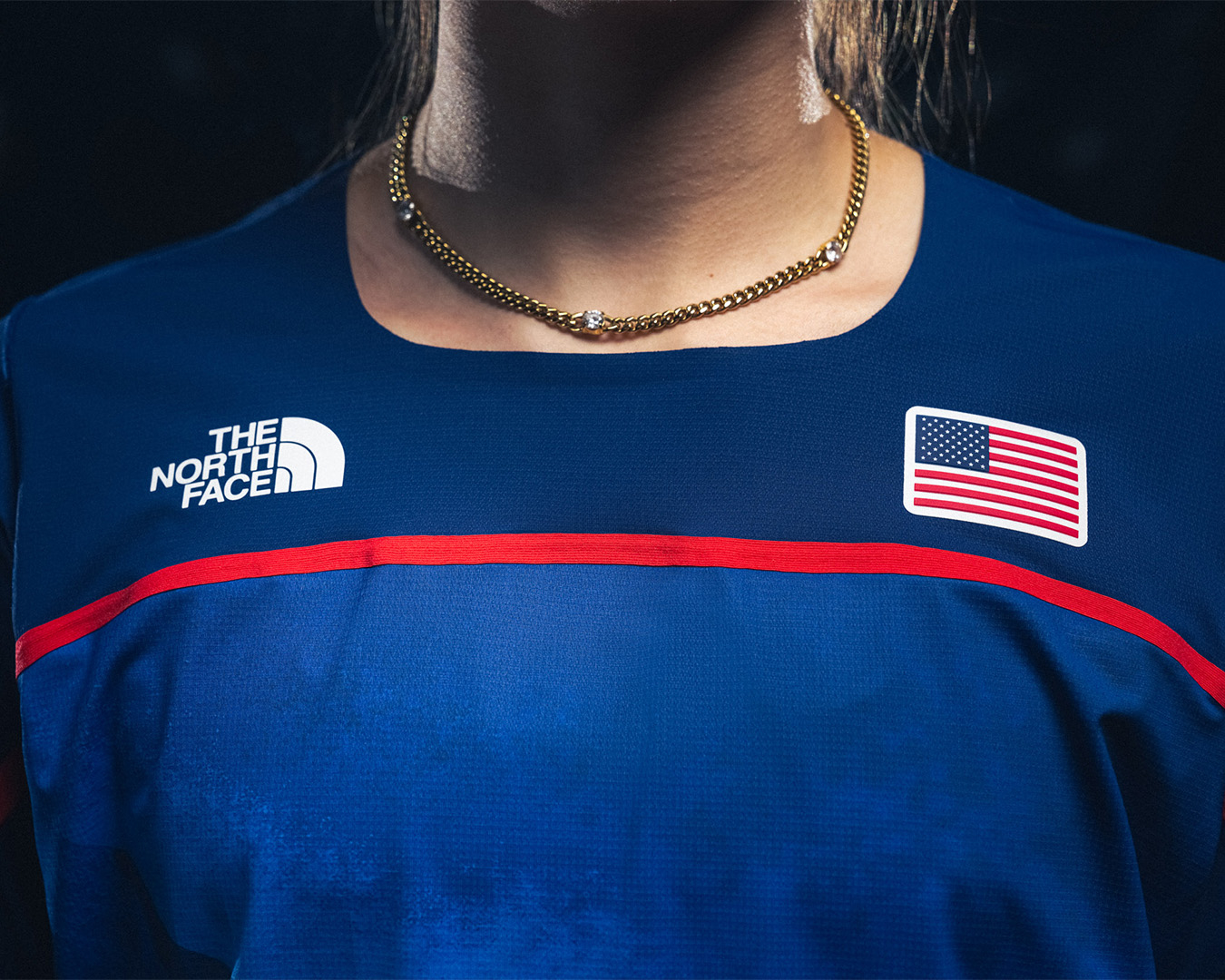 Close-up of a person&#x27;s torso wearing a The North Face top with a US flag on the right chest