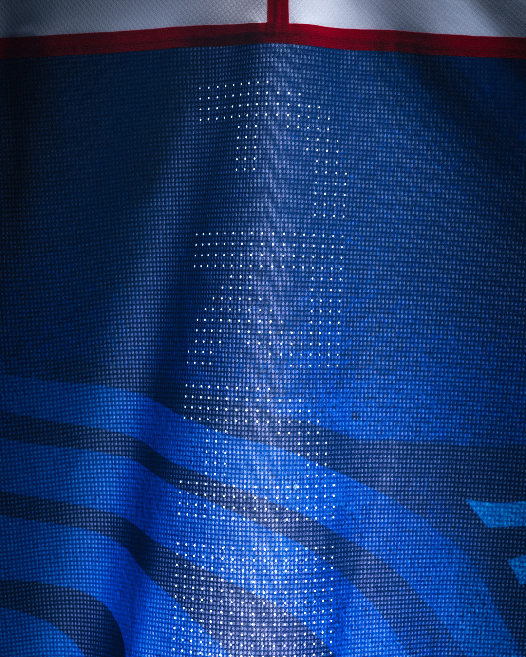 Close-up of a blue fabric texture with light shining through, creating a shadow of a person&#x27;s profile