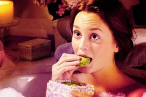 Woman sitting, eating a cucumber slice and holding a patterned box
