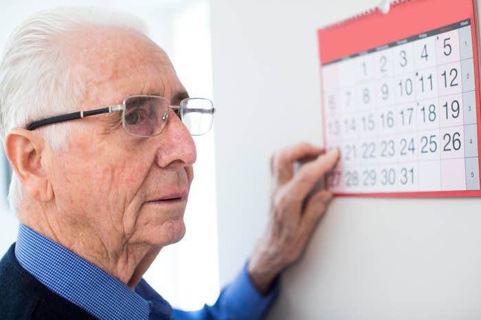 Elderly person pointing at a date on a wall calendar