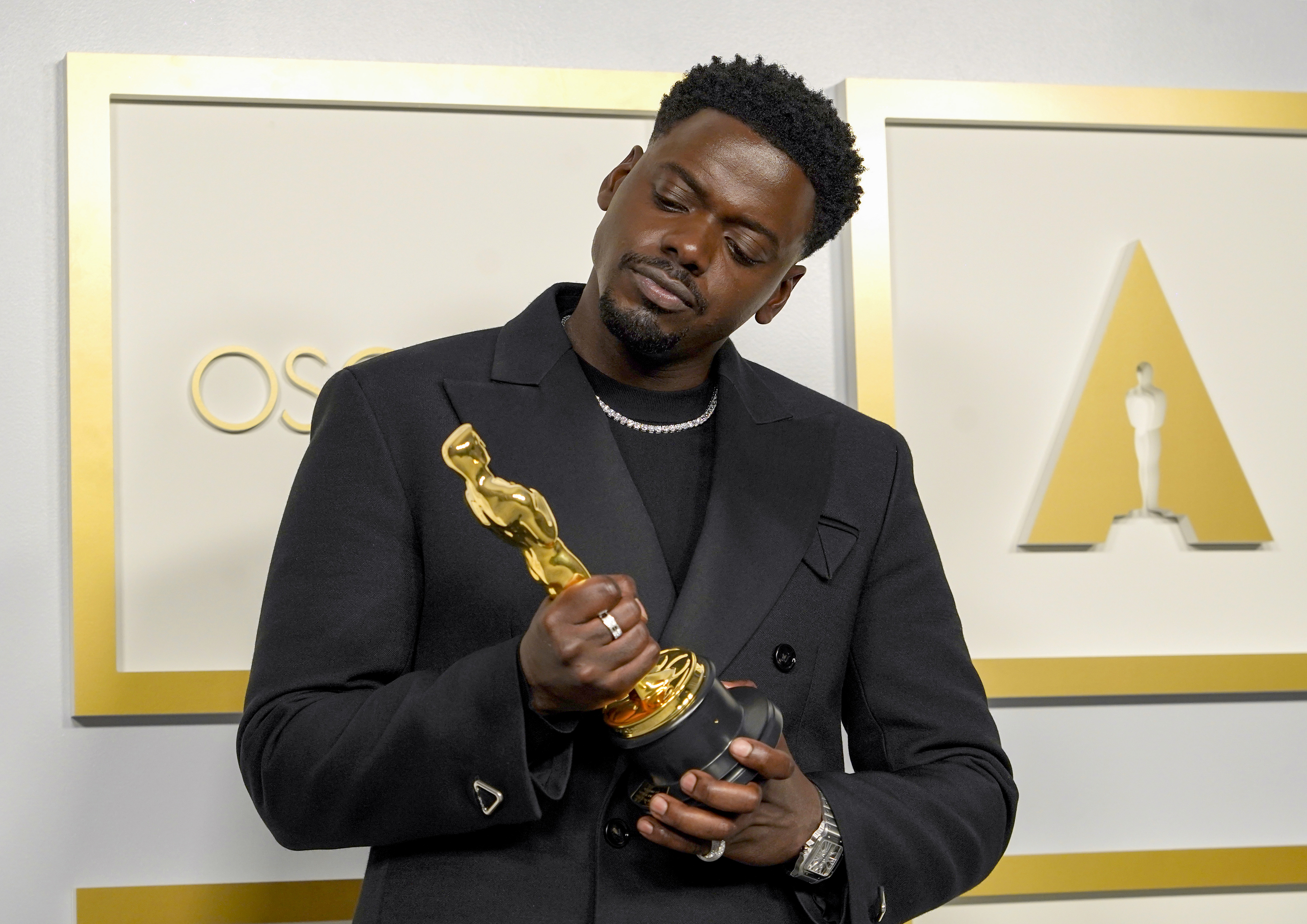 Daniel Kaluuya in a suit holding his Oscar statuette