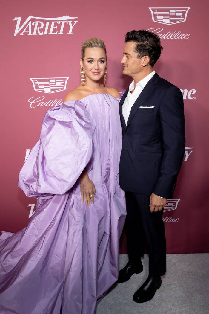 Orlando Bloom looks at Katy Perry as they stand on the red carpet