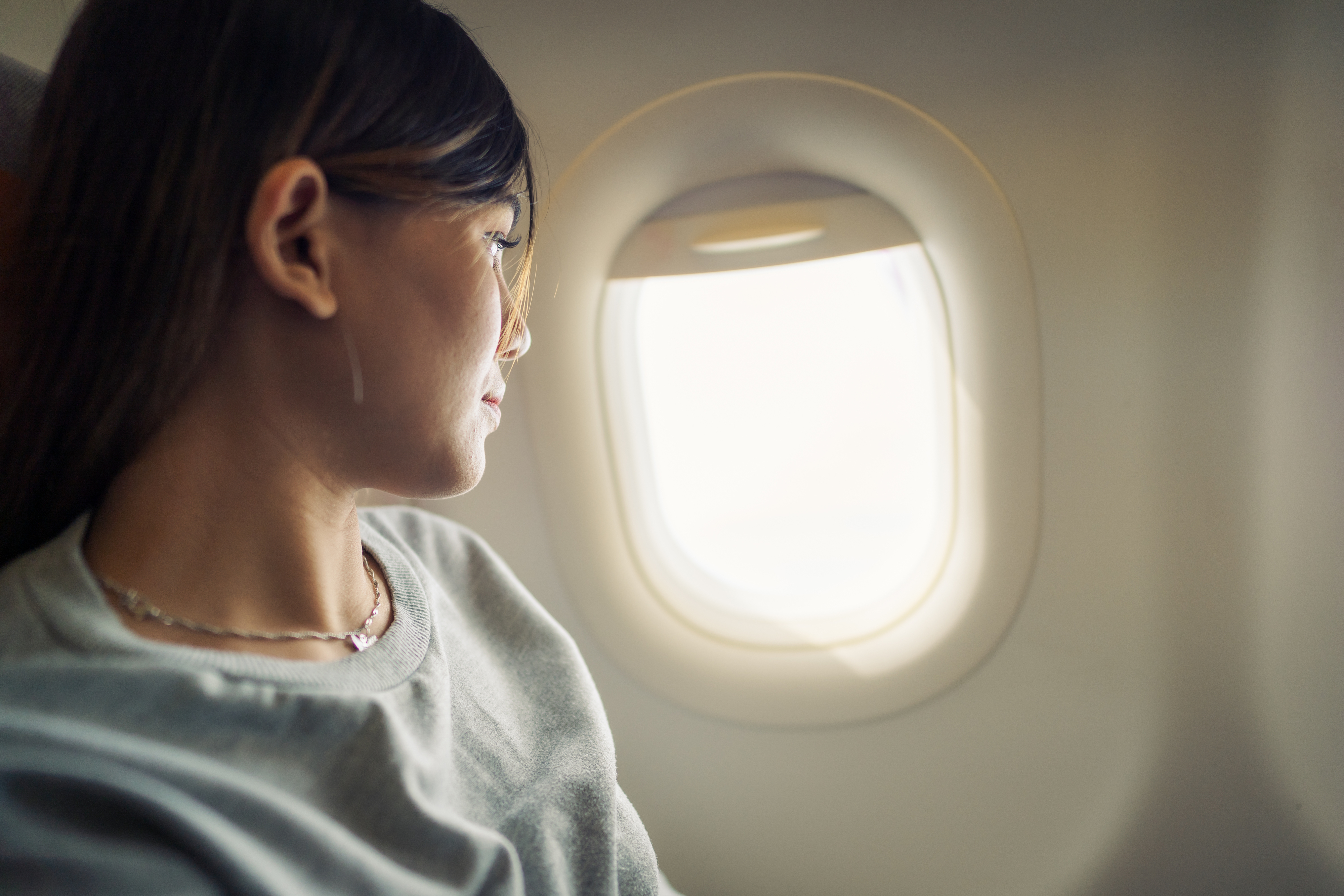 Woman looking out the window of an airplane, reflecting on travel