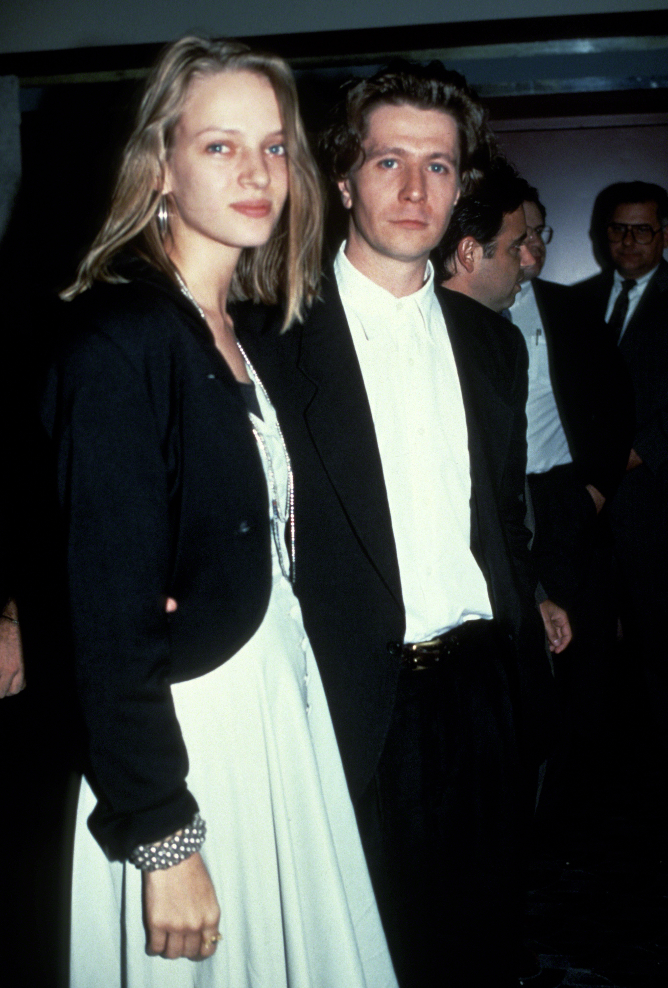 Uma Thurman in a white dress with a black jacket, and Andrew McCarthy in a black suit and white shirt