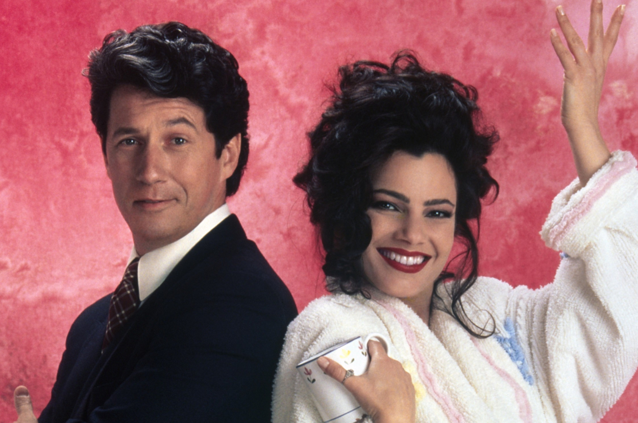 Two characters from the show "The Nanny" smiling, man in suit, woman in striped robe with hair rollers