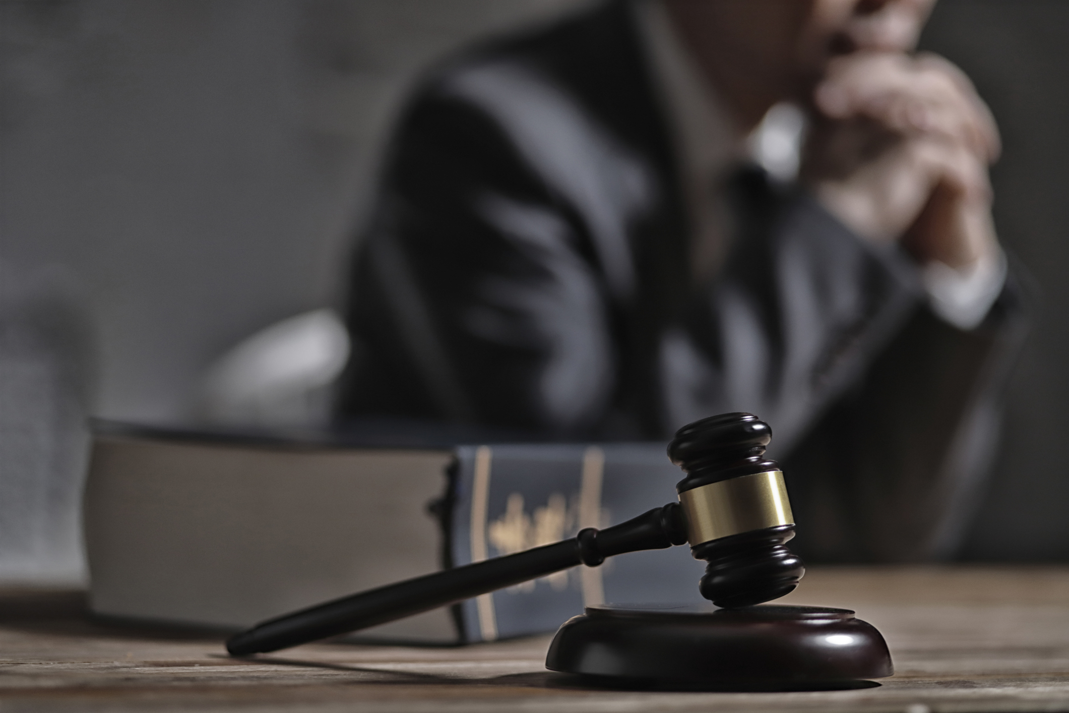 Person pondering at desk with gavel, symbolizing legal profession or judiciary