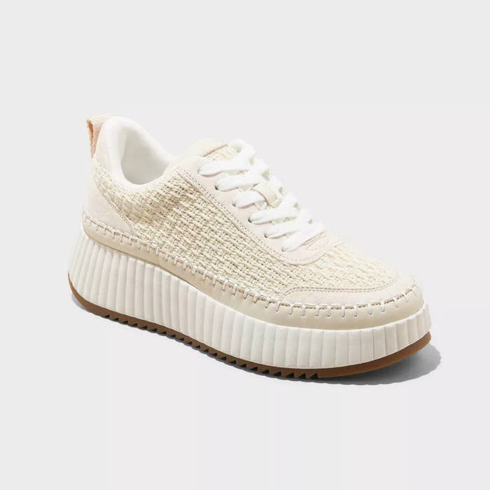 Cream-colored knitted sneaker with a ribbed sole displayed against a plain background