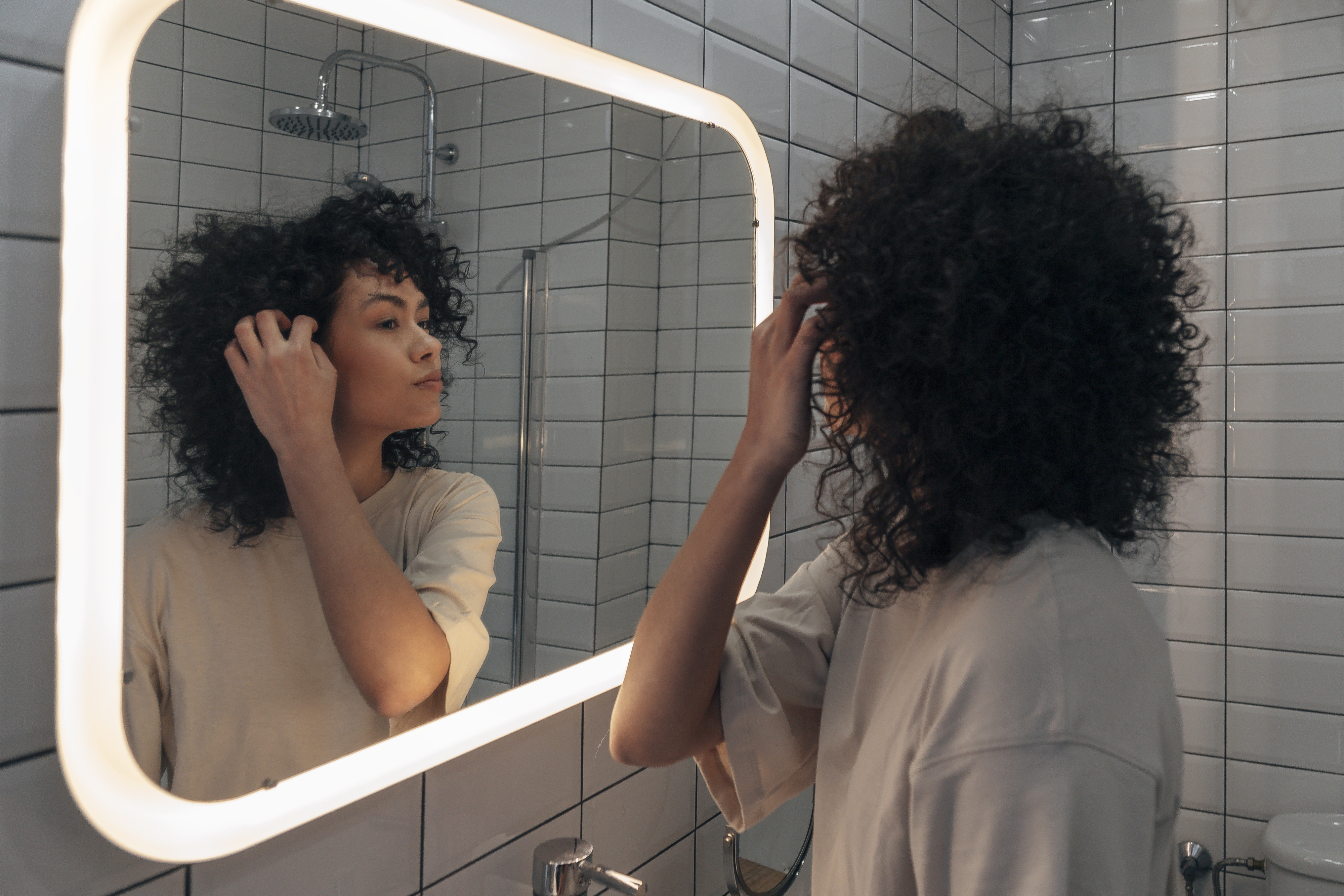 Person adjusting their hair while looking in a mirror