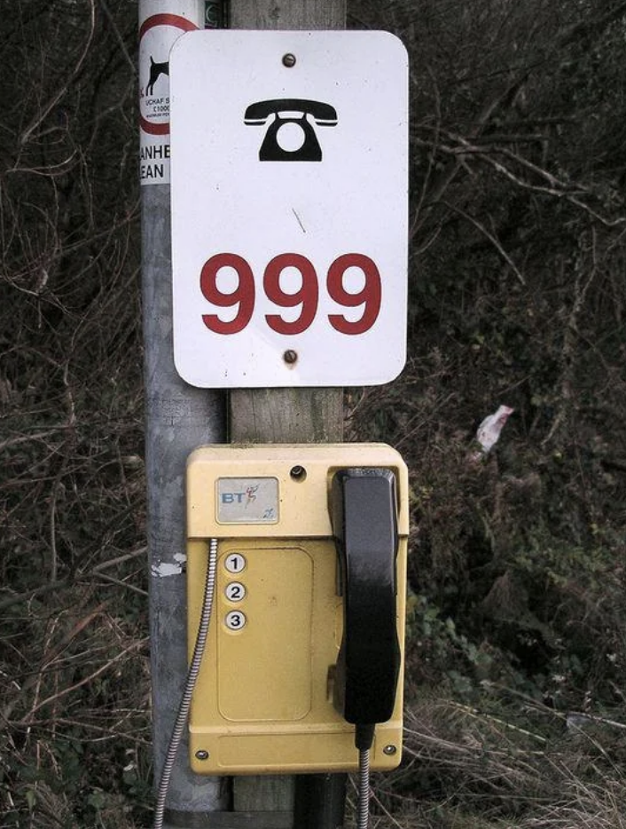 Emergency phone with number &#x27;999&#x27; above it, attached to a pole for public use